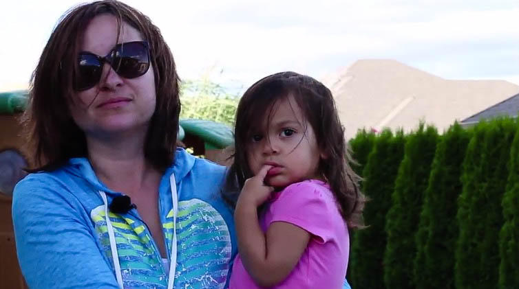 A woman in a blue shirt holds a little girl in a pink shirt