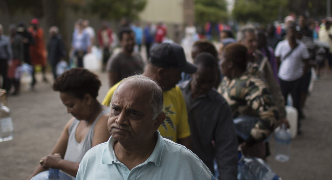 Residents wait to fill containers at a source for natural spring water in Cape Town, South Africa. CREDIT: Bram Janssen/AP