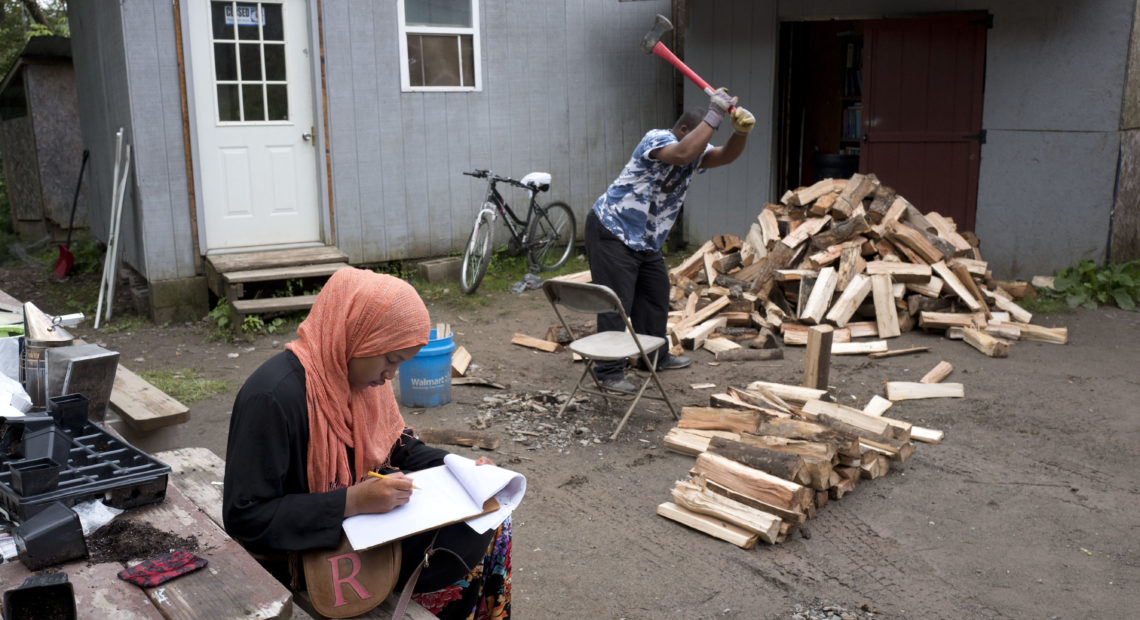 Seen in 2017, a girl studies for school while a man chops wood in the Muslim enclave of Islamberg in Tompkins, N.Y. Four people have been arrested in an alleged plot to attack the community. Mark Lennihan/AP