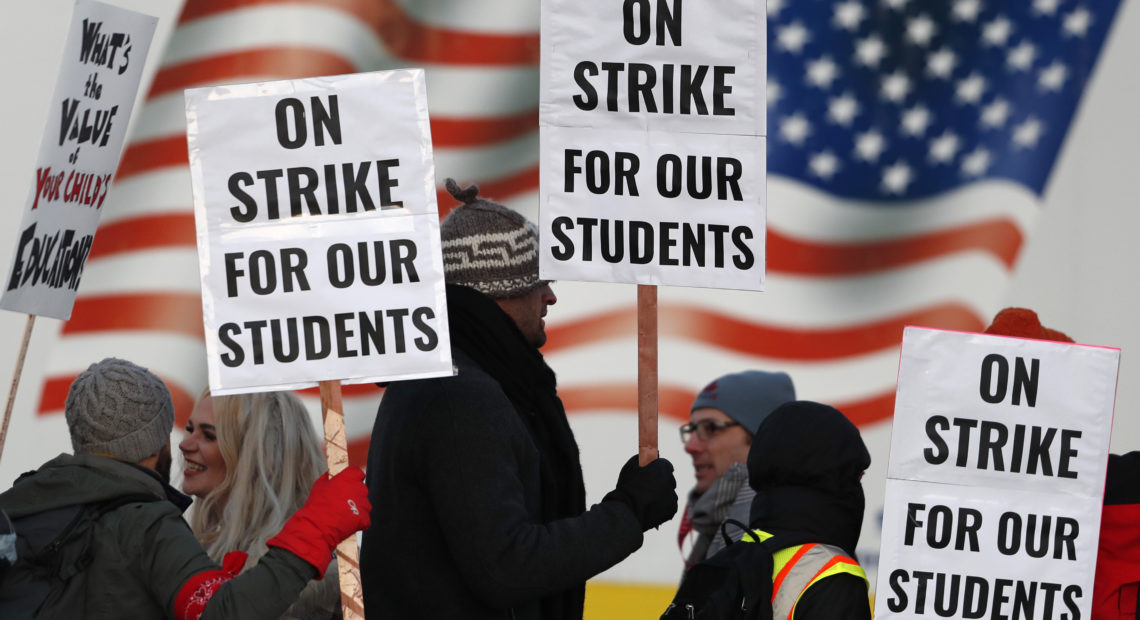 Teachers carry placards as they walk a picket line outside South High School early Monday in Denver. A new lawsuit alleges students with disabilities will be harmed by the strike.