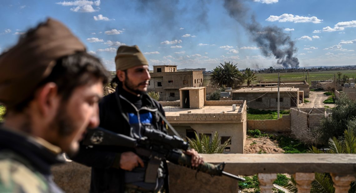 U.S.-backed fighters stand guard on a building during shelling of the Islamic State's last holdout in the town of Baghouz, Syria, on March 3. Bulent Kilic/AFP/Getty Images