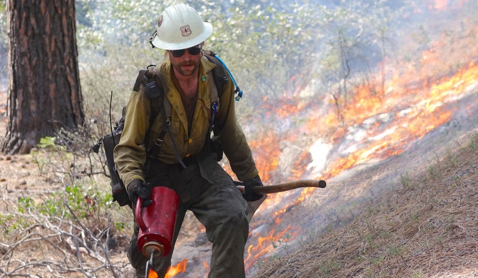 A member of the Wolf Creek Hotshots uses a drip torch to ignite the forest floor during a prescribed burn near Sisters, Oregon.