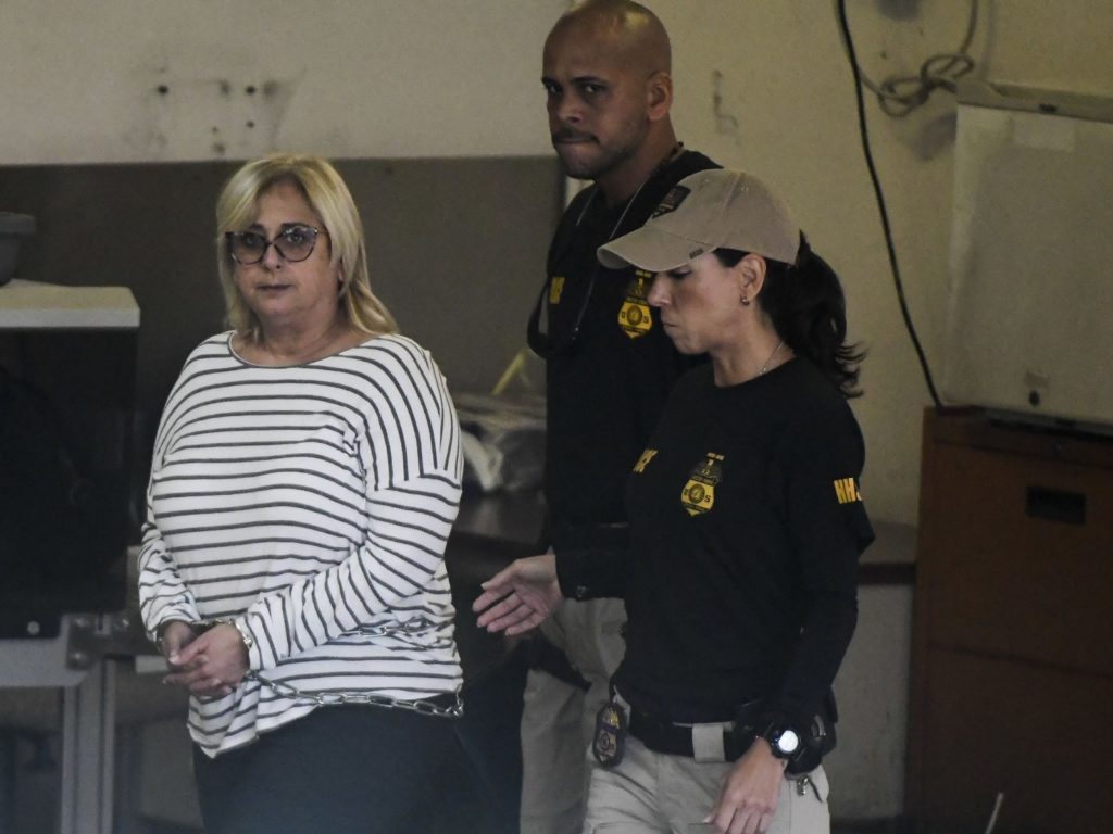 Federal agents escort former Puerto Rico Health Insurance Administration head Ángela Ávila-Marrero, who was arrested on Wednesday as part of a corruption investigation that resulted in an indictment against six defendants. CREDIT: Carlos Giusti/AP