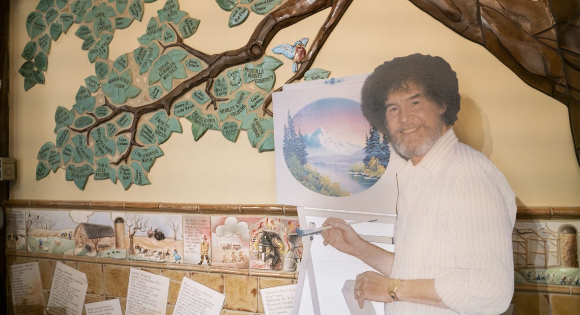 A life size cut out of Bob Ross stands up against the wall where the historical tree of the Franklin Park Arts Center is painted. Bob Ross Inc. is located in Herndon, Va., which is only 27 miles from the exhibit. According to managing director, Elizabeth Bracey, the exhibit was intentionally kept close to headquarters.