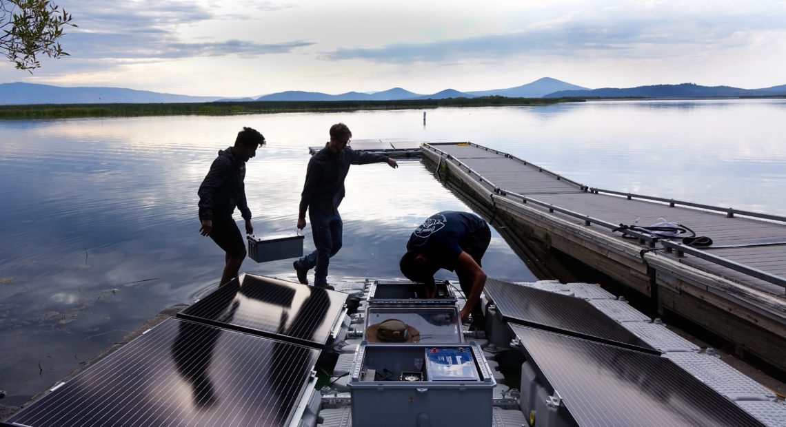 Mohammed Bawazeer and Ian Riley carry a battery that will power the aeration system on Upper Klamath Lake for 32 hours, even if the sun isn't shining.