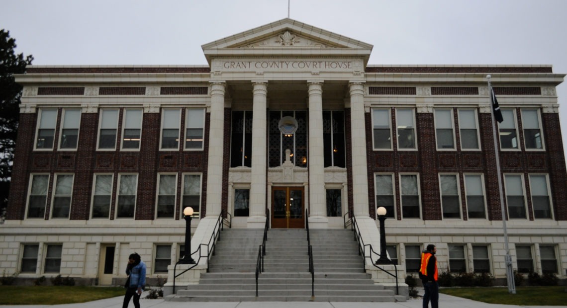 The Grant County Courthouse in Ephrata, pictured in November 2019, where federal immigration authorities have been spotted arresting undocumented people going to court since 2017. In front of the courthouse steps, Brenda Rodriguez with the Washington Immigrant Solidarity Network takes a phone call while a volunteer hands out “Know Your Rights” pamphlets. CREDIT: Enrique Pérez de la Rosa/NWPB