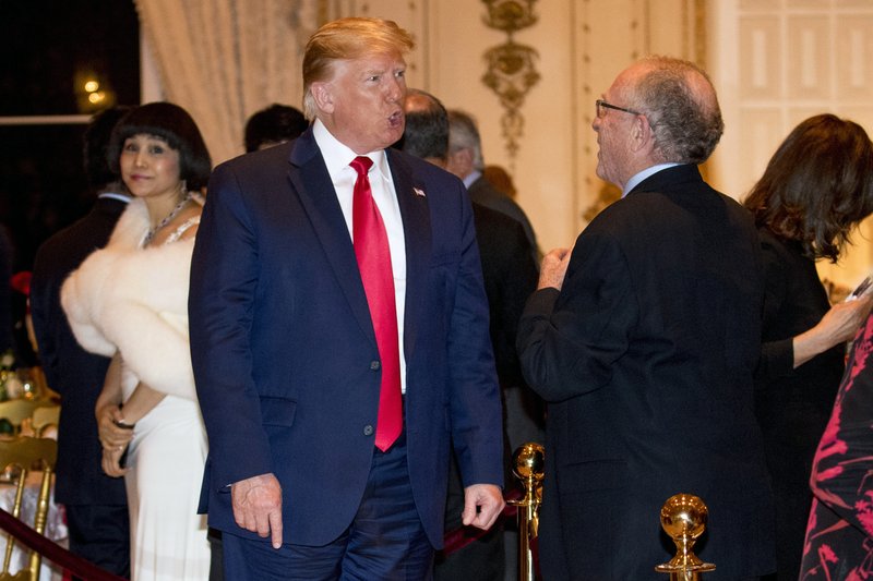 File photo. President Donald Trump speaks to attorney and impeachment defense team member Alan Dershowitz, right, as he arrives for Christmas Eve dinner at Mar-a-lago in Palm Beach, Fla. Dershowitz says he hasn't changed at all and has a long history of representing people whose views he doesn't necessarily agree with. Dershowitz is part of President Donald Trump's defense team at the Senate impeachment trial. CREDIT: Andrew Harnik/AP