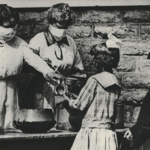 Volunteers wearing gauze masks at a street kitchen in Cincinnati serve food to children of families afflicted by the flu pandemic in the winter of 1918-1919.