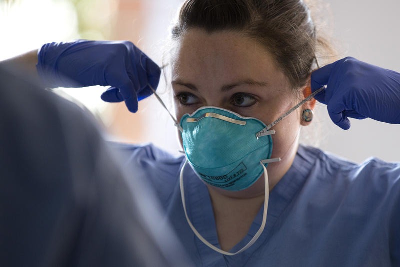 Jess White, a registered nurse at UW Northwest, demonstrates to another nurse how to properly remove a mask on Thursday, March 12, 2020, at UW Medicine's drive-through testing clinic in Seattle. CREDIT: Megan Farmer/KUOW