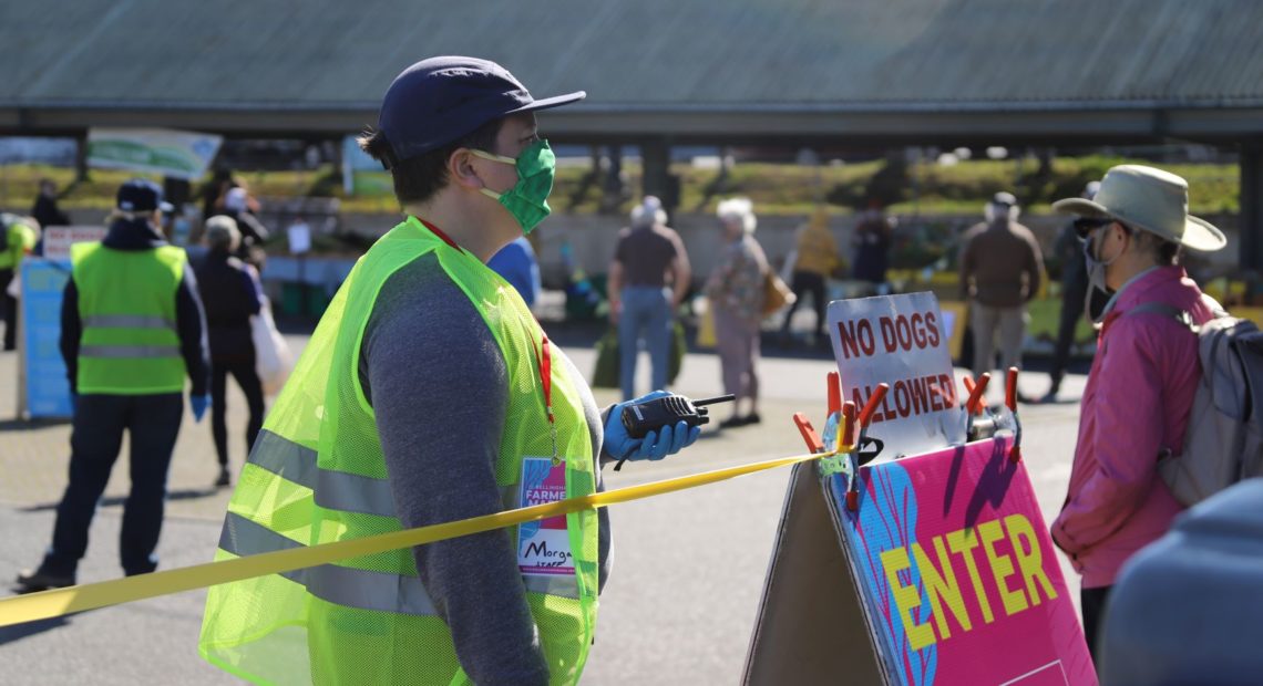 Morgan Henry Kerr of Bellingham's Farmers Market monitors the new market entrance to monitor the number of people in the market so that physical distancing is maintained at all times.