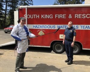 Reporter Tom Banse sports a protective gown made of Tyvek house wrap while interviewing COVID-19 task force member Lt. Greg Willett.