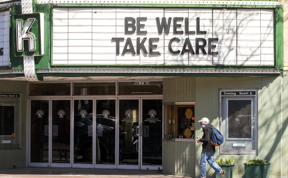 A pedestrian wearing a mask passing under the marquee at the Kenworthy Performing Arts Centre