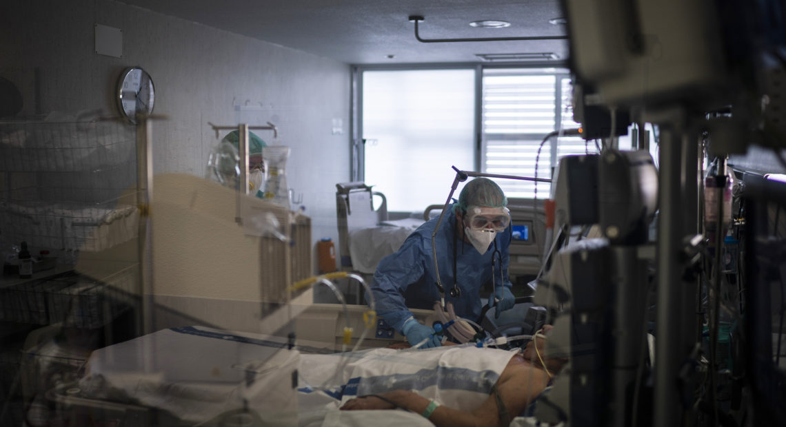 Health care workers assist a COVID-19 patient in Spain. Some evidence from Europe and China suggests an overzealous immune response may be contributing to the severe illness in some patients. CREDIT: Felipe Dana/AP