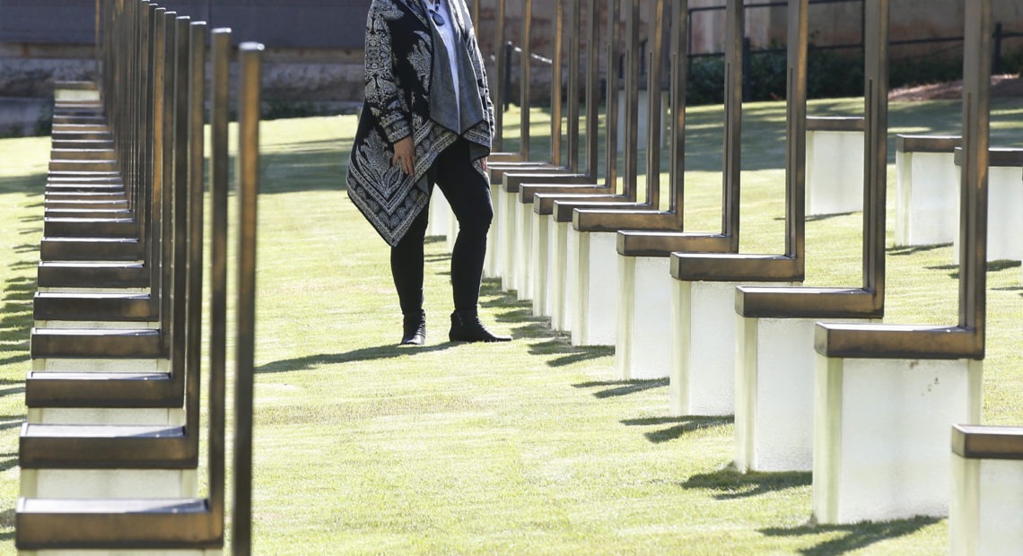 Lynne Gist stands at her sister's chair in the Field of Empty Chairs at the Oklahoma City National Memorial and Museum