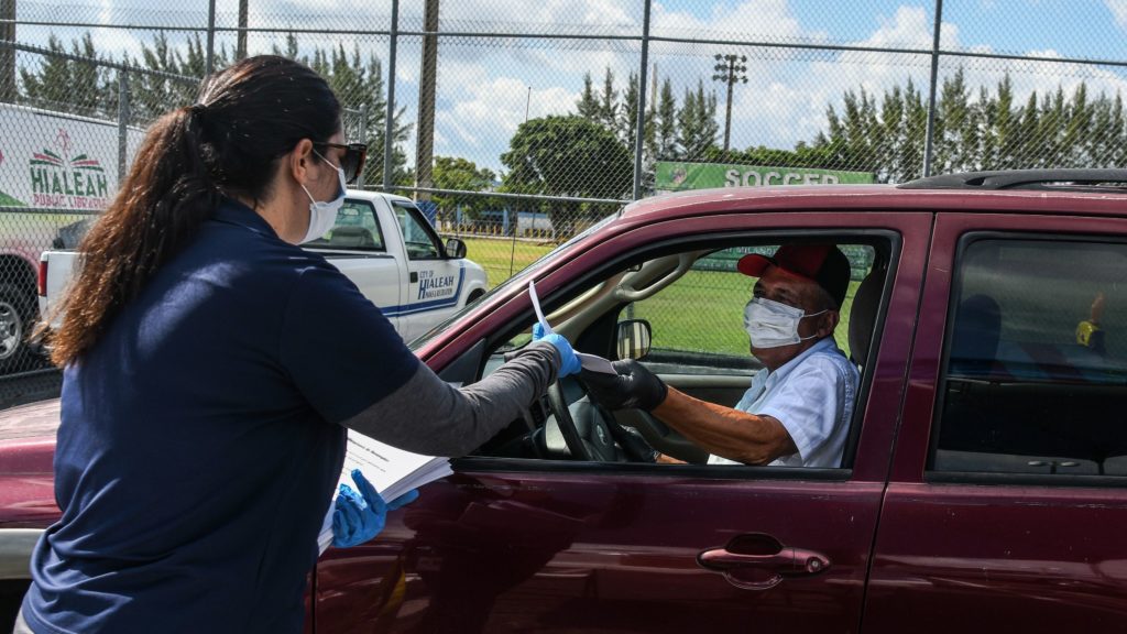 A man collects unemployment forms at a drive-through collection point outside of a library in Hialeah, Fla., on Wednesday. CREDIT: Chandan Khanna/AFP via Getty Images