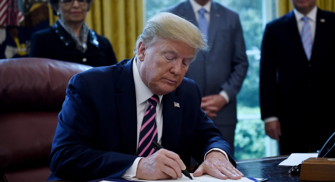 President Trump a new coronavirus economic aid package, largely targeted to support small businesses, in the Oval Office on Friday. CREDIT: Olivier Douliery/AFP via Getty Images