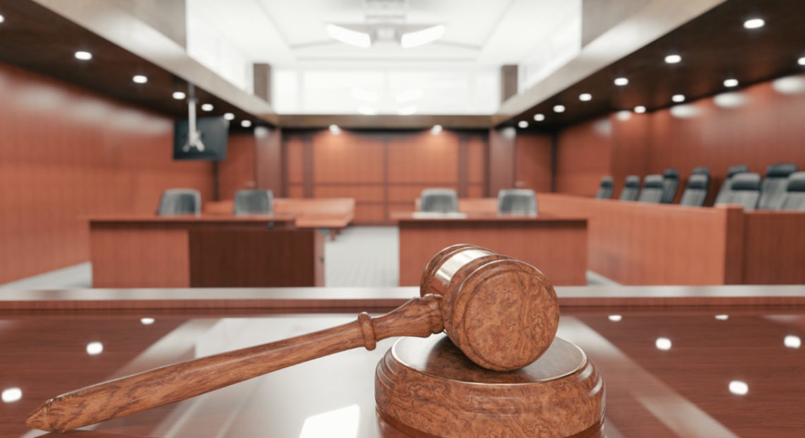 Interior of an empty courtroom with gavel and sounding block on the desk.