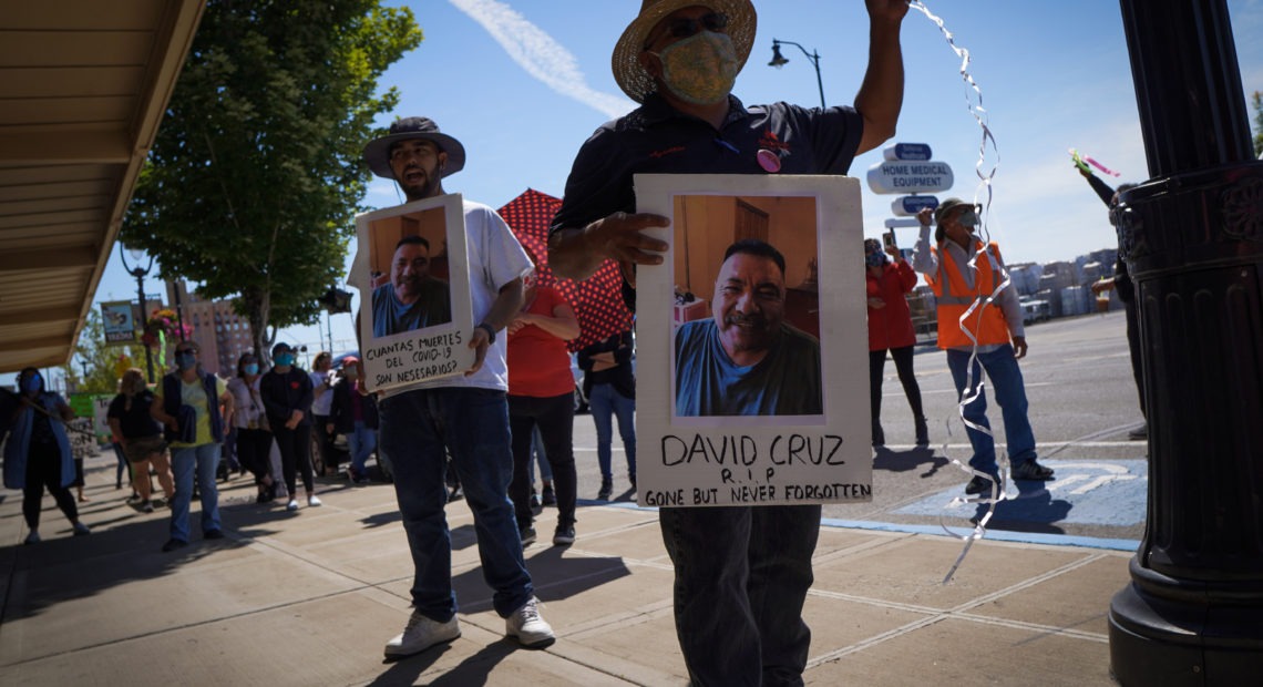 Farmworkers in Yakima’s fruit-packing industry walked off production lines in May and went on strike, demanding more protections against the coronavirus pandemic. Above, Emmanuel Anguiano-Mendoza (left) and Agustin López hold posters featuring David Cruz, a worker who died on May 30. CREDIT: Enrique Pérez de la Rosa/NWPB