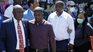 All four former Minneapolis police officers now face criminal charges in the death of George Floyd. Attorney Ben Crump, left, escorts Floyd's son Quincy Mason, second from left, on Wednesday during a visit to the memorial where Floyd was arrested in Minneapolis.