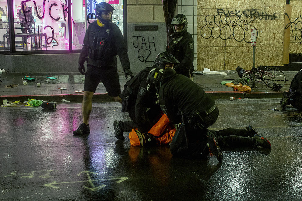 Bystanders yell at a police officer to remove his knee from a detained person’s neck while SPD made arrests at a vandalized T-Mobile store downtown, May 30, 2020. A moment later a fellow officer forcibly removed the officer's knee from the man's neck. CREDIT: Shaminder Dulai/Crosscut