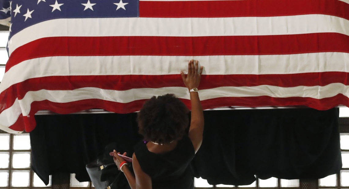 A mourner pauses by the casket of Rep. John Lewis lying in repose at the Georgia state Capitol on Wednesday in Atlanta. Lewis, who carried the struggle against racial discrimination from Southern battlegrounds of the 1960s to the halls of Congress, died on July 17. CREDIT: John Bazemore/AP