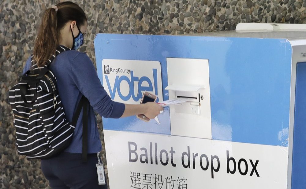 A person drops off a ballot for Washington state's primary election, Tuesday, Aug. 4, 2020, at a collection box at the King County Administration Building in Seattle. CREDIT: Ted S. Warren/AP