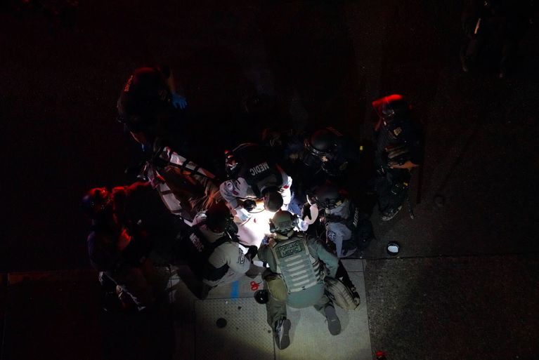 Medics attend to an apparent gunshot victim on the ground as a pro-Trump car caravan moved through downtown Portland, Ore., Aug. 29, 2020. CREDIT: Jonathan Levinson / OPB