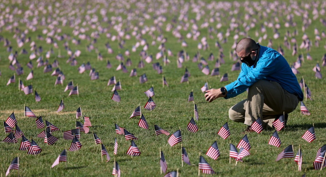 The U.S. hit a tragic milestone Tuesday, recording more than 200,000 coronavirus deaths. Here, Chris Duncan, whose mother, Constance, 75, died from COVID-19 on her birthday, visits a COVID Memorial Project installation of 20,000 American flags on the National Mall. The flags are on the grounds of the Washington Monument, facing the White House. Win McNamee/Getty Images