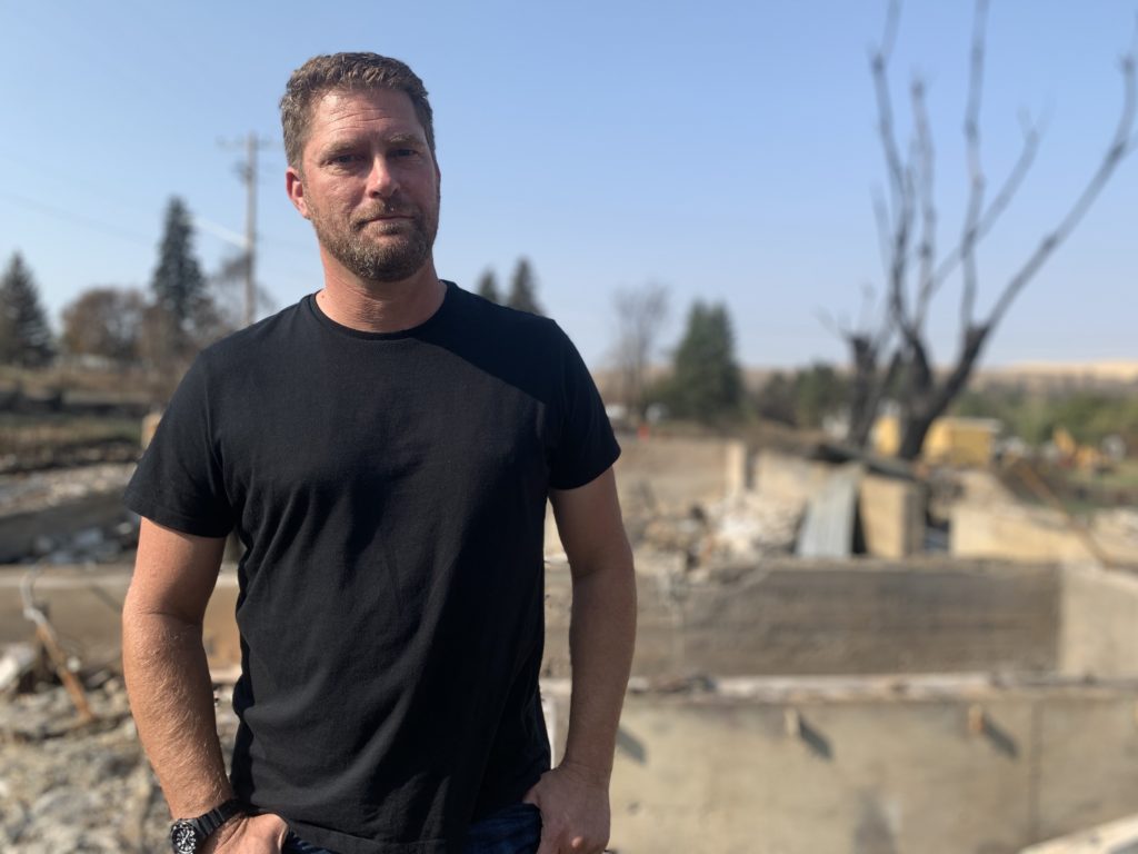 Scott Hokonson, a Malden town council member and volunteer firefighter, stands in the rubble of his home which was destroyed by the wildfire. CREDIT: Kirk Siegler/NPR