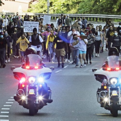 In this June 1, 2020, photo, police on motorcycles escort a protest march in Tacoma against police and the death of George Floyd in Minneapolis days earlier. Washington state lawmakers and activists are setting an ambitious agenda for police reform in the upcoming legislative session. They say they hope to make it easier to decertify officers for misconduct, to bar the use of police dogs to make arrests, and to create an independent statewide agency to investigate police. CREDIT: Photo/Ted S. Warren