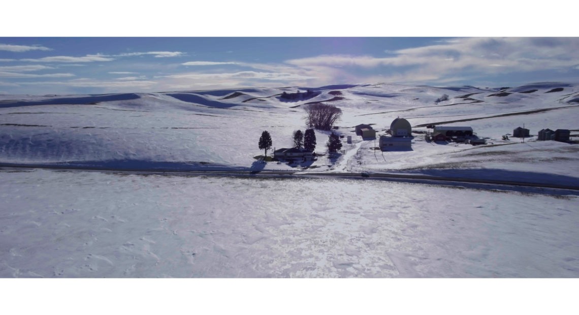 Drone shot of snow covered hills and farmhouse