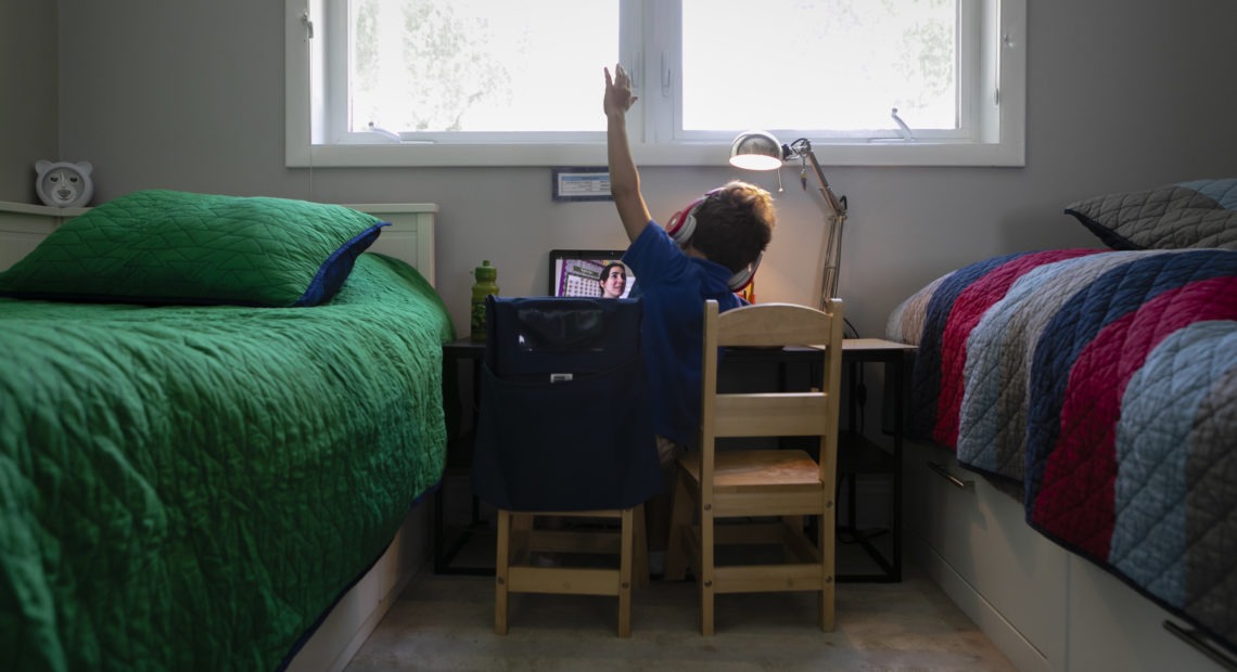 A student raises his hand while attending an online class from home in Miami on Sept. 3. Eva Marie Uzcategui/Bloomberg via Getty Images