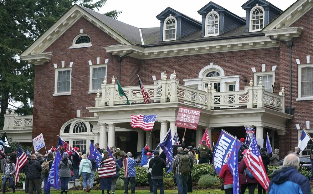 Protesters stand outside the Washington Governor's Mansion after getting through a perimeter fence, Wednesday, Jan. 6, 2021, at the Capitol in Olympia following a protest against the counting of electoral votes in Washington, DC, affirming President-elect Joe Biden's victory. The area was eventually cleared by police. CREDIT: Ted S. Warren/AP