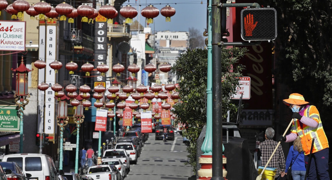 In this Jan. 31, 2020, file photo, a masked worker cleans a street in the Chinatown district in San Francisco. Police and volunteers have increased their street presence after a series of violent attacks against older Asian residents in Bay Area cities stoked fear and subdued the celebratory mood leading up to the Lunar New Year. (AP Photo/Ben Margot, File) Ben Margot/AP