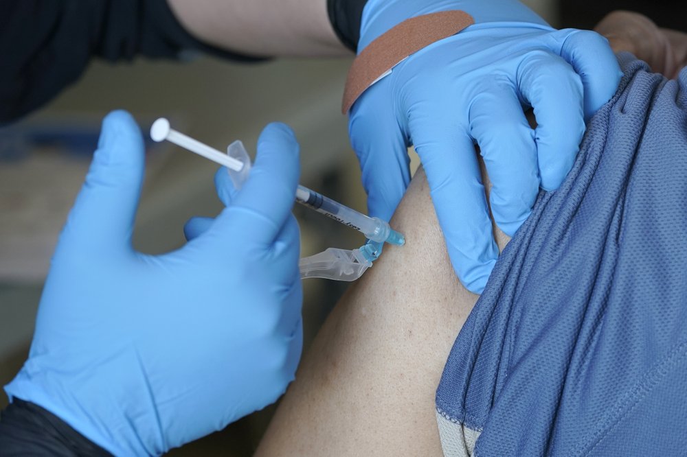 Kristin May, an EMT with the Seattle Fire Dept., gives the first dose of the Moderna COVID-19 vaccine to a patient at a City of Seattle community COVID-19 testing and vaccination clinic in Seattle's Rainier Beach neighborhood in February 2021. CREDIT: Ted S. Warren/AP