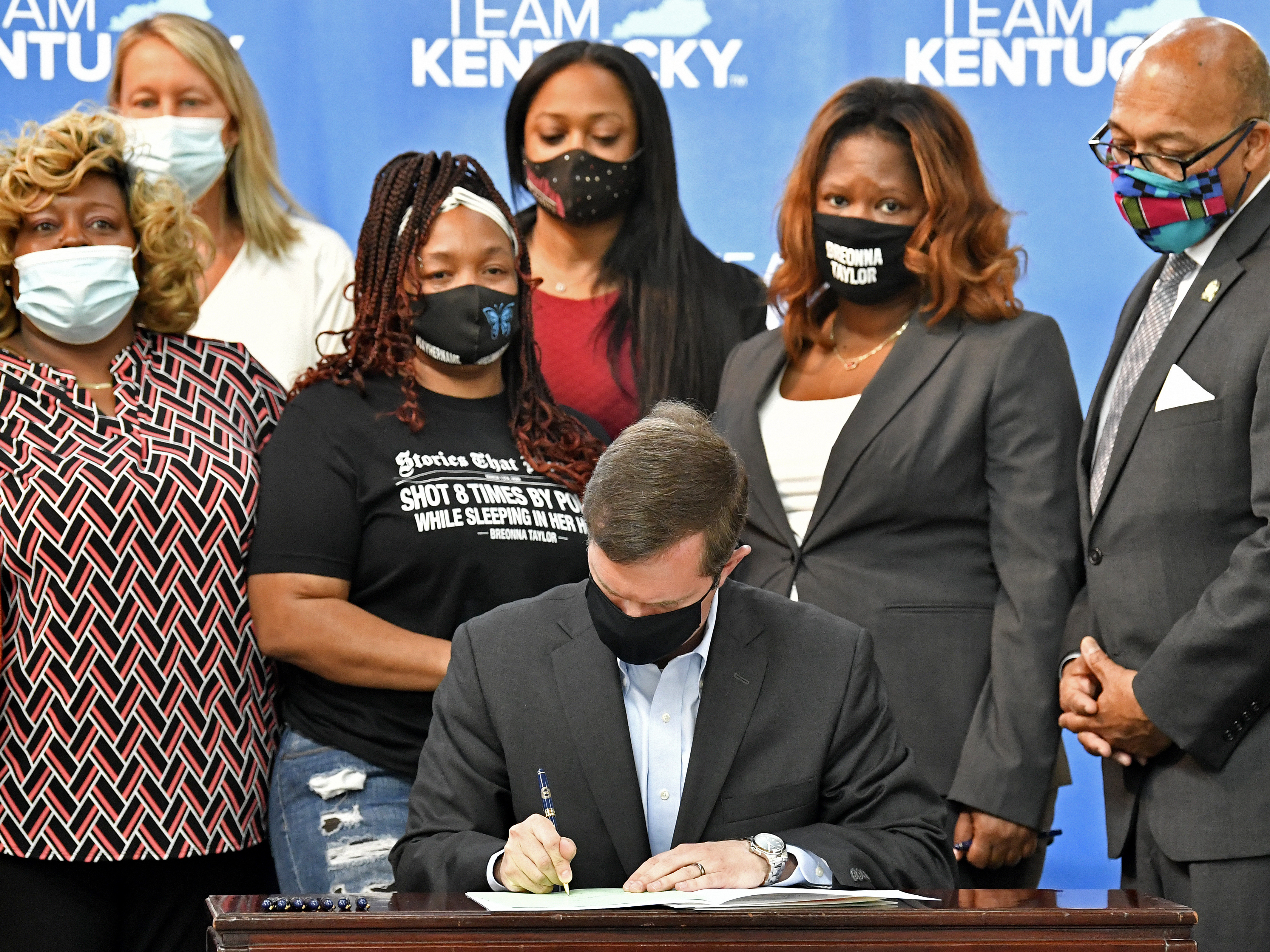 Kentucky Gov. Andy Beshear signs a bill on Friday limiting the use of no-knock warrants statewide. The governor was surrounded by members of Breonna Taylor's family including her mother, Tamika Palmer (standing behind Beshear at left). CREDIT: Timothy D. Easley/AP