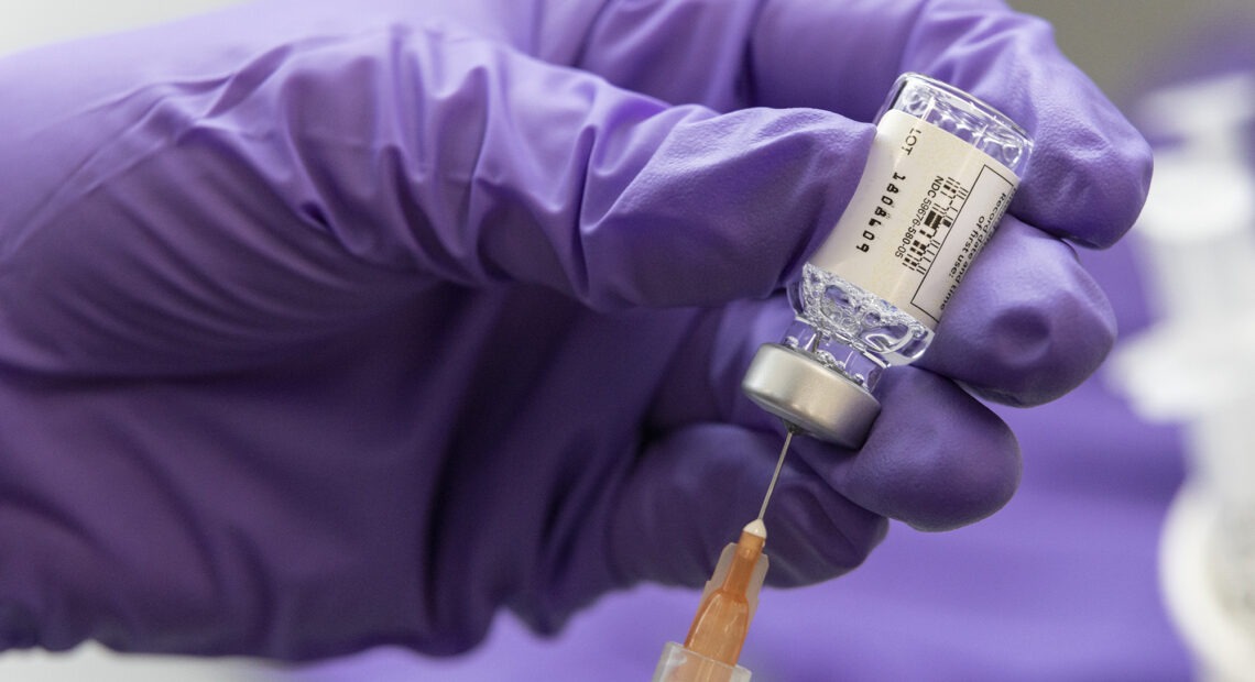 syringe going into a vial of COVID-19 vaccine