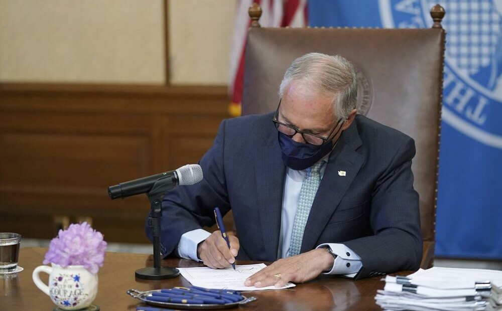 Washington Gov. Jay Inslee signs a bill into law on May 12, 2021, at the Capitol in Olympia, Wash., that prohibits openly carrying guns and other weapons at the state Capitol and protests statewide. CREDIT: Ted S. Warren/AP