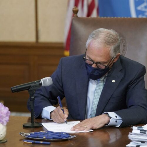 Washington Gov. Jay Inslee signs a bill into law on May 12, 2021, at the Capitol in Olympia, Wash., that prohibits openly carrying guns and other weapons at the state Capitol and protests statewide. CREDIT: Ted S. Warren/AP