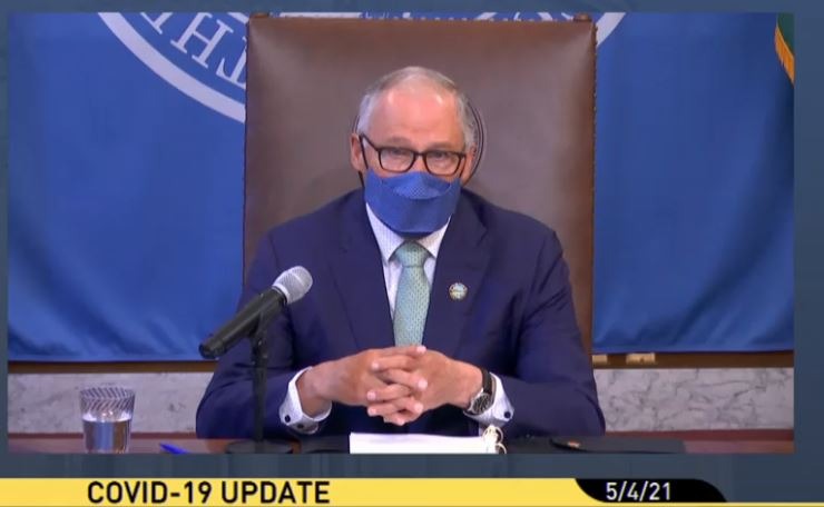 Washington Governor Jay Inslee wearing a mask and speaking from his desk during a press conference