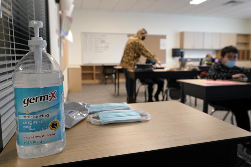 File photo. Hand sanitizer, wipes, and surgical masks rest on a desk in a fourth-grade classroom at Elk Ridge Elementary School in Buckley, Wash. State authorities said May 13, 2021, all schools in the state must provide full-time, in-person education for students for the 2021-22 school year and that students and staff will still be required to wear masks as a COVID-19 mitigation effort. CREDIT: Ted S. Warren / AP