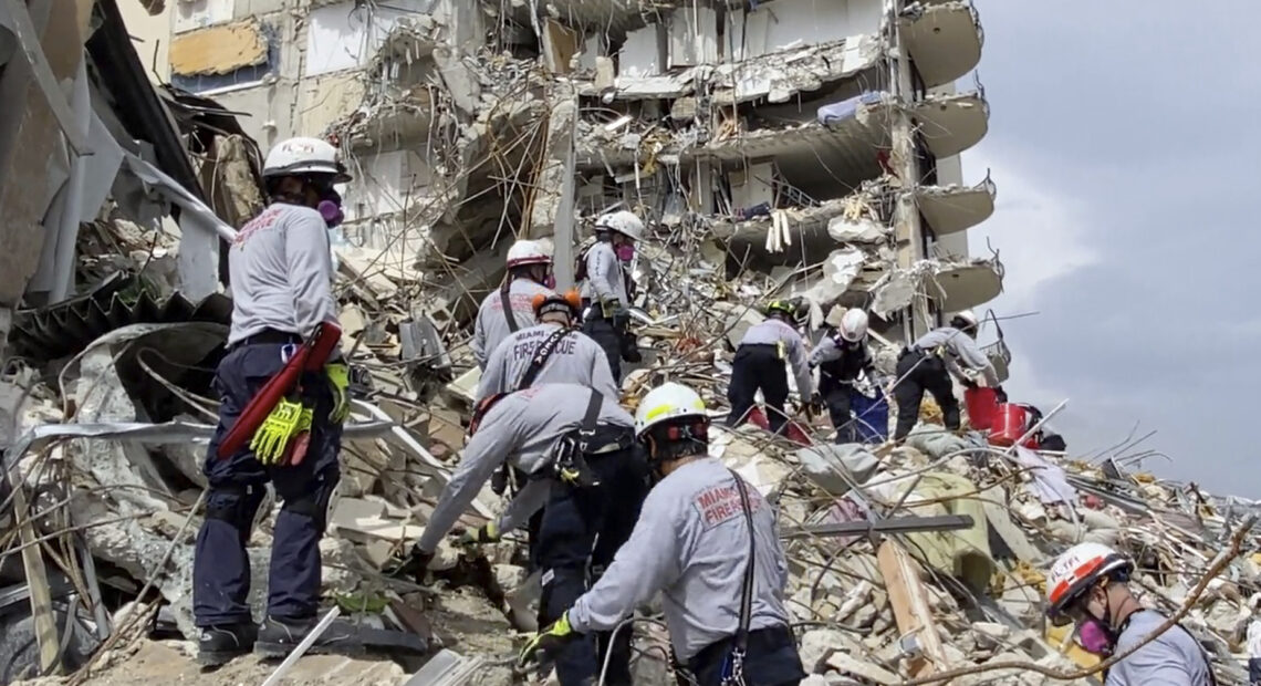 In this photo provided by Miami-Dade Fire Rescue, search-and-rescue personnel search for survivors through the rubble at the Champlain Towers South Condo in Surfside, Fla., on Friday. Via AP