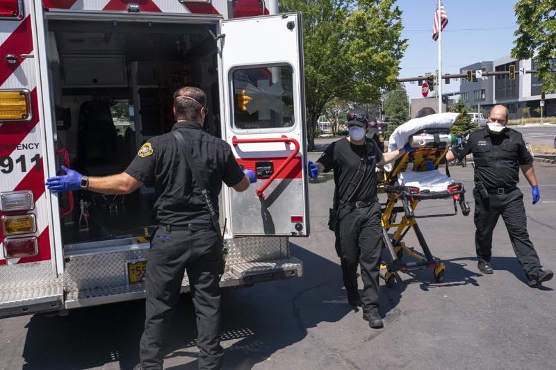 Salem Fire Department paramedics and employees of Falck Northwest ambulances respond to a heat exposure call during a heat wave, June 26, 2021, in Salem, Ore. CREDIT: Nathan Howard/AP