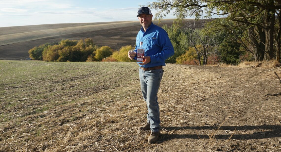 Nathan Rea holds a bottle of the first Salmon-Safe American single malt whiskey. Rea grew the barley used to make the whiskey in Walla Walla.