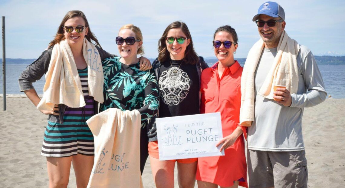 A handful of people standing on the beach who participated in the Puget Plunge after the EPA Region 10 first approved the No Discharge Zone for the sound in 2018.