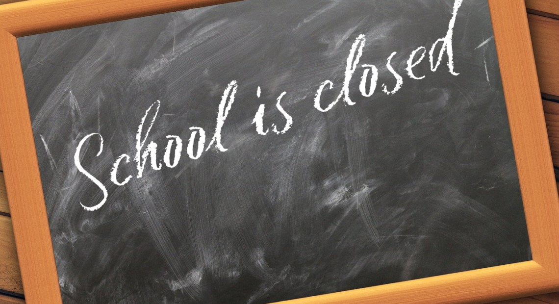 A black chalk board with the writing, school closed on it.