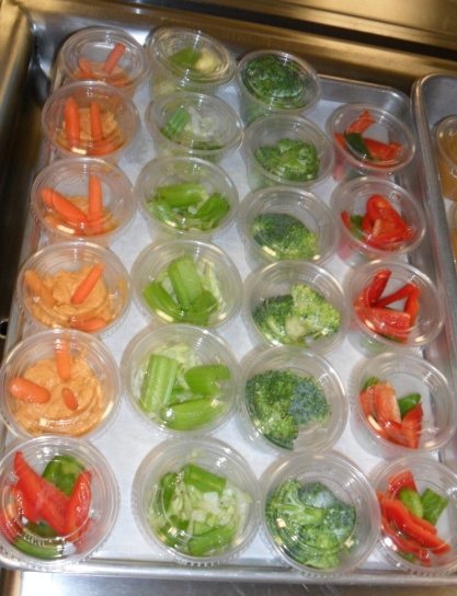 Color coordinated cups of carrots, broccoli and red peppers for school lunches