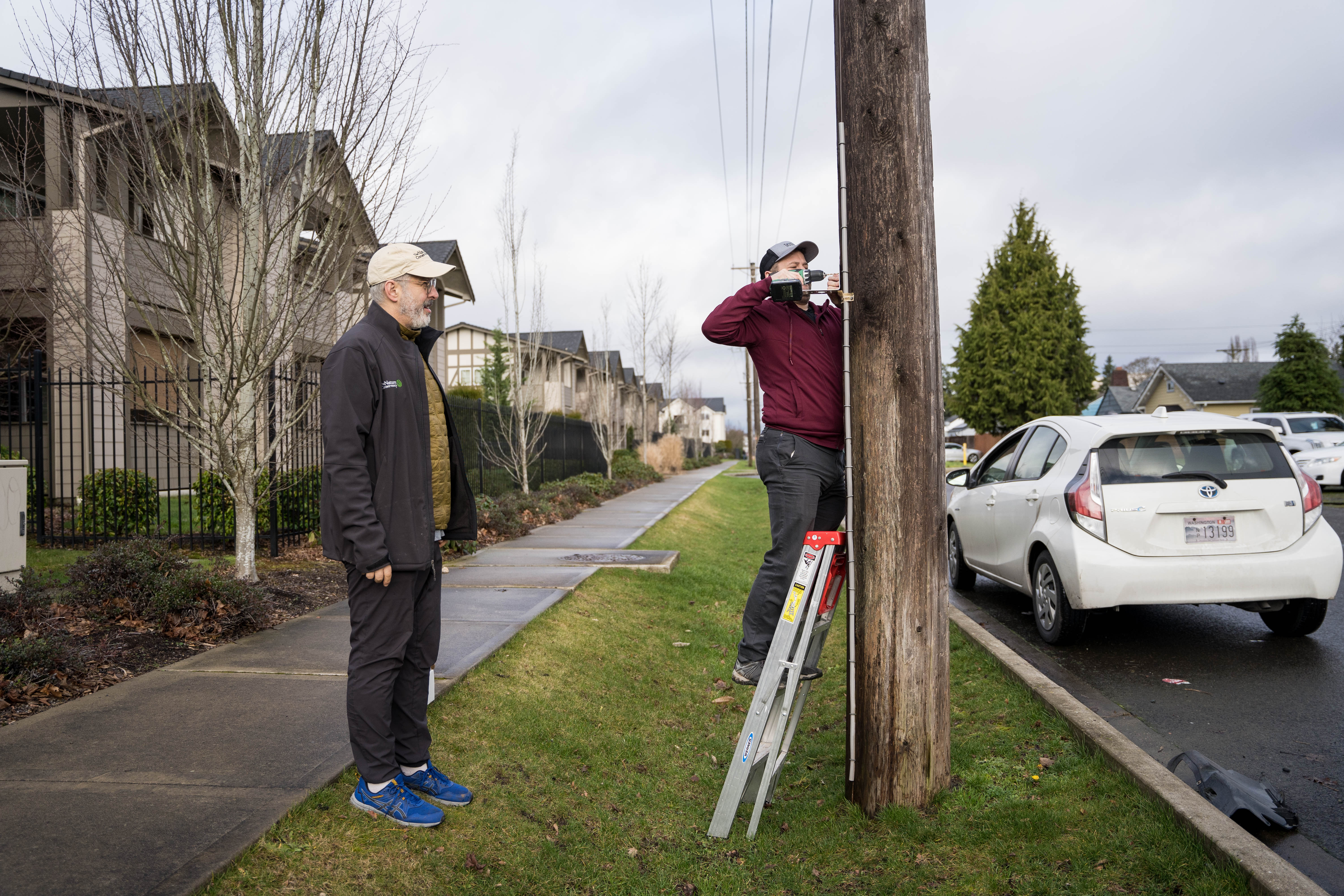 Nature Conservancy lead scientist, lead scientist Phil Levin, left, and Lowell Wyse, right, of the Tacoma Tree Foundation install a temperature logging device in South Tacoma. This will help scientists measure the impact that planting more vegetation has on temperatures in urban areas. Photo courtesy of Courtney Baxter/TNC