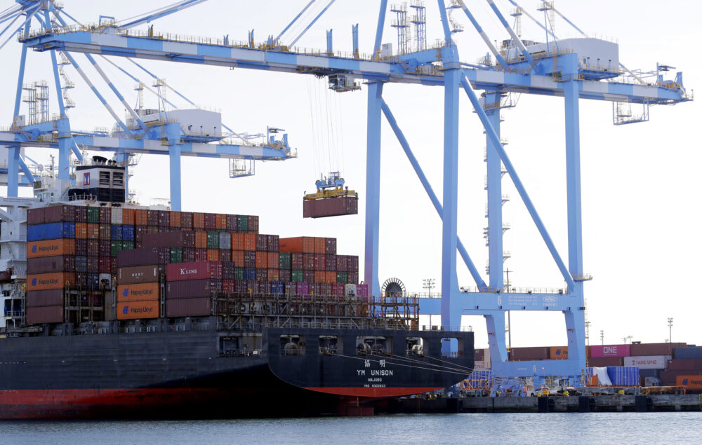 Multicolored shipping containers are loaded off a cargo ship by blue cranes at the Port of Tacoma.