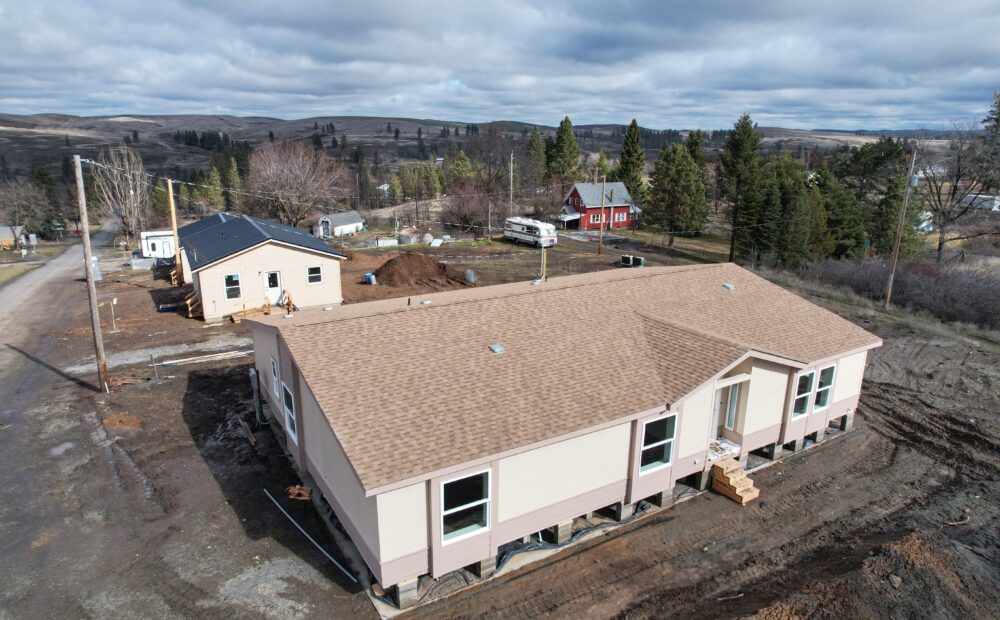 A bird's eye view shows newly constructed houses upon a brown and muddy street.